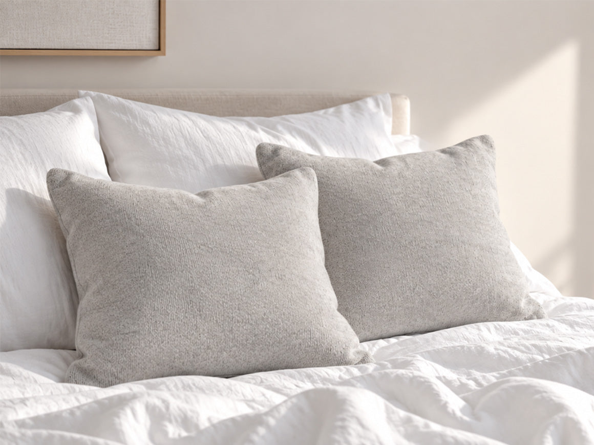 Grey cashmere cushion and bedspread styled with light bedding in a contemporary bedroom